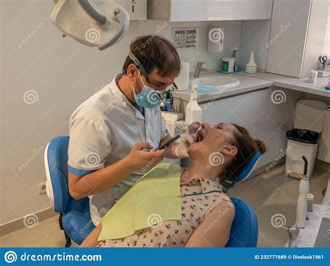 Dental Clinic Dentist Treats Teeth Of A Young Adult Woman Stock Image