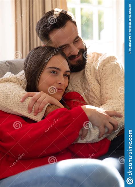 Happy Caucasian Couple Sitting On Couch In Living Room Smiling And Embracing Stock Image