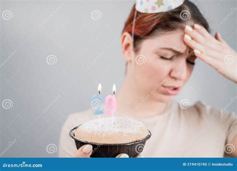 unhappy woman holding a cake with candles for her 29th birthday the girl cries about the loss