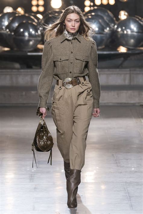 A Woman Walking Down A Runway Carrying A Handbag