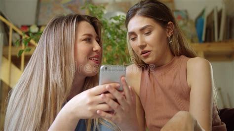 Two Pretty Lgbt Girls Are Sitting On The Sofa And Chatting With Their Friends On The Internet