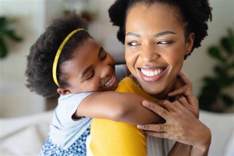 Cerca De Una Chica Afroamericana Abrazando A Su Madre Desde Atrás En Casa Imagen De Archivo
