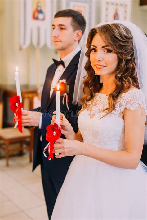Bride And Groom Holding Lighted Candles During The Traditional Wedding