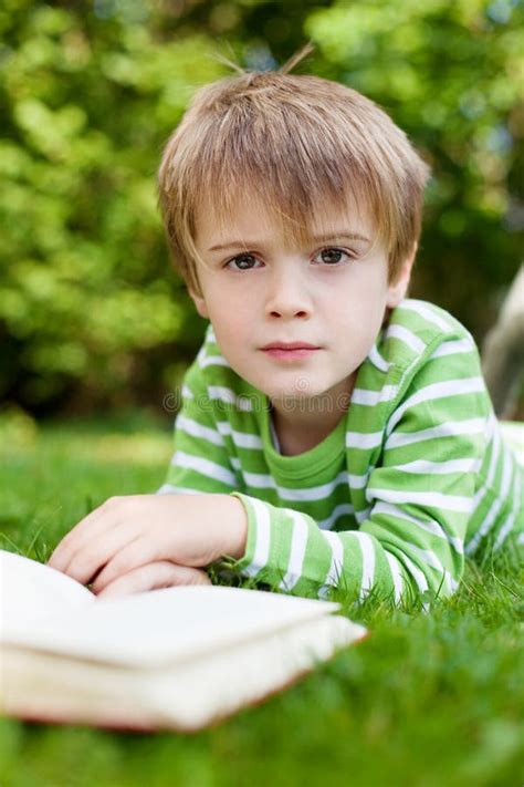 Cute Young Boy Sitting On Grass And Reading Stock Photo Image Of Calm