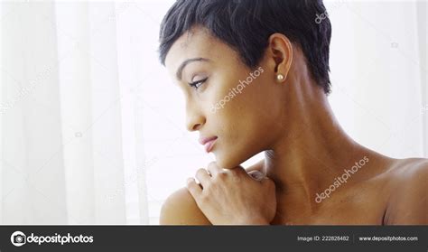 Beautiful Topless Black Woman Hugging Herself Looking Out Window Stock