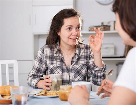 Two Woman Friends Talking And Drinking Tea In The Kitchen Stock Image