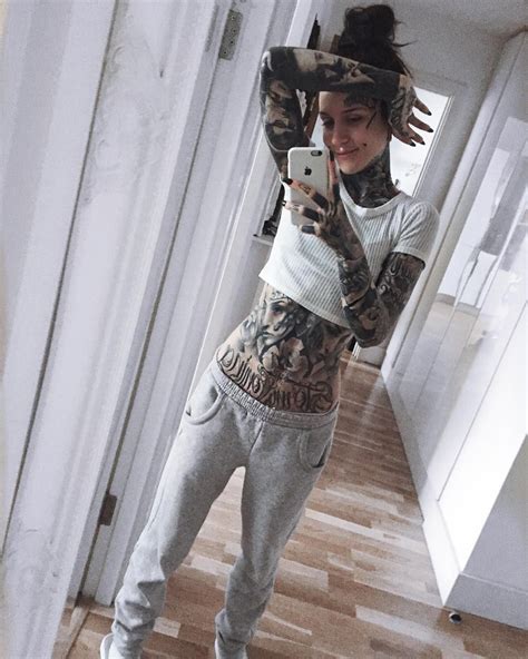 a woman taking a selfie with her cell phone in front of her face and tattoos on her arm