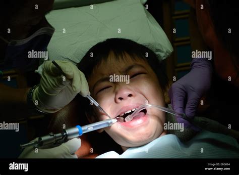 Dentist Holding Syringe For Injection Of Asian Child Close Up Stock