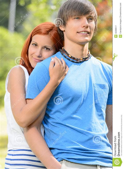 Teenage Girlfriend Hugging Her Boyfriend In Park Stock