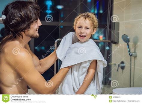 Dad Wipes His Son With A Towel After A Shower In The Evening Before Going To Sleep On The