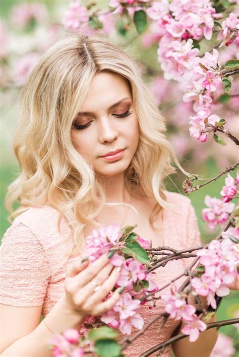 Portrait Of A Blonde Woman In Pink Flowers Spring Garden Stock Photo