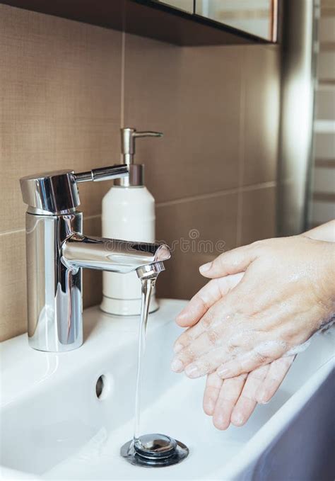 Young Woman Washing Her Hands With Liquid Soap Under The Water Tap In
