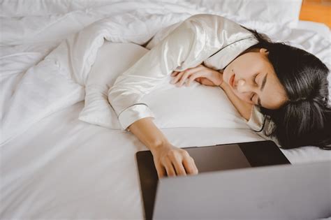 하루 동안 침대에 누워 아시아 여자 그녀는 흰색 침대에서 랩톱 컴퓨터로 작업 한 후 게으르고 잔다 그녀는 일하는 것에