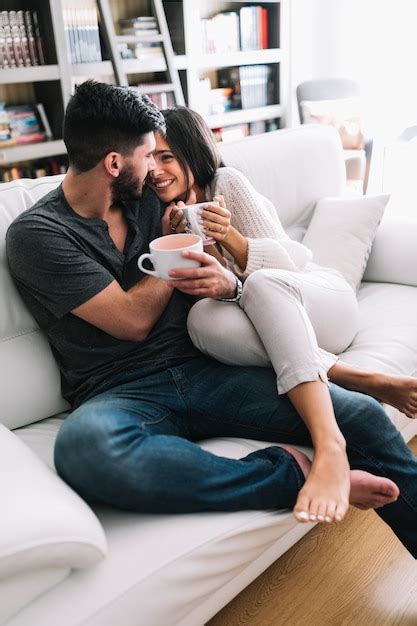 Free Photo Romantic Couple Sitting On Sofa Holding Coffee Cup Looking