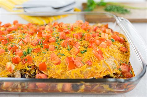 Layered chicken enchilada casserole is assembled, one layer at a time. Layered Healthy Chicken Enchilada Casserole for an Easy Weeknight