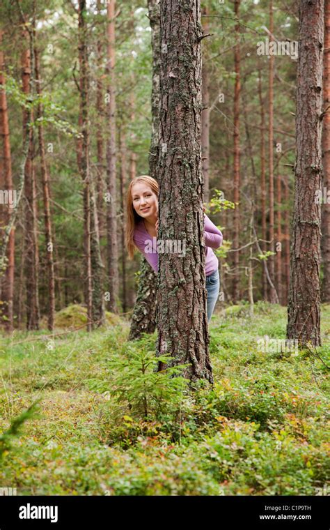 Young Woman Hiding Behind Tree In Forest Stock Photo Alamy
