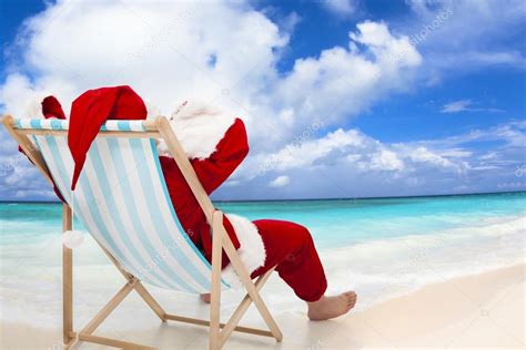 Santa Claus Sitting On Beach Chairs With Blue Sky And Cloud Stock Photo