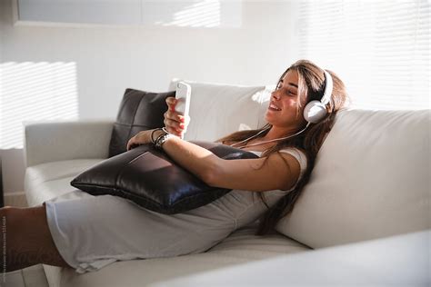 Happy Woman Listening The Music On Sofa With Cellphone By Stocksy Contributor Michela Ravasio