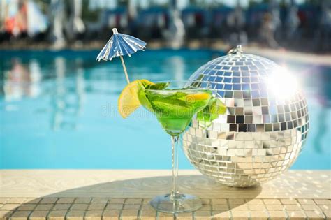 Shiny Disco Ball And Refreshing Cocktail On Edge Of Swimming Pool Party Items Stock Image