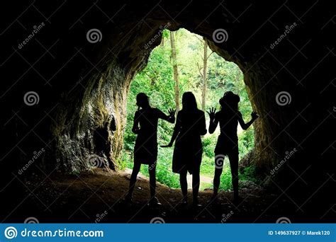 Female Silhouettes At The Entrance To Natural Cave In The Forrest Stock