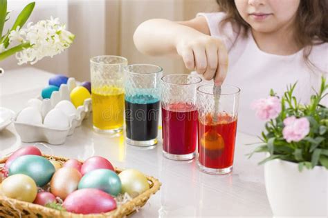 Cute Little Girl Painting Easter Eggs In Glasses With Liquid Dye Stock