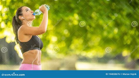 Young Sporty Woman Drinking Water From A Bottle After Exercising At The