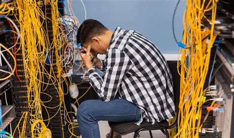 A Man Is Sitting On A Chair In Front Of A Rack Of Wires And Wires