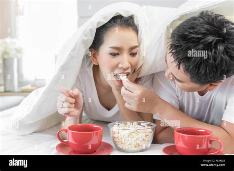 Young Asian Couples Having Breakfast On Bed Together In Bedroom Of Contemporary House For Modern