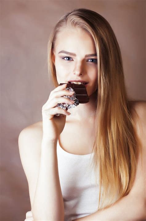 Young Cute Blond Girl Eating Chocolate And Smiling On Brown Background Lifestyle People Concept