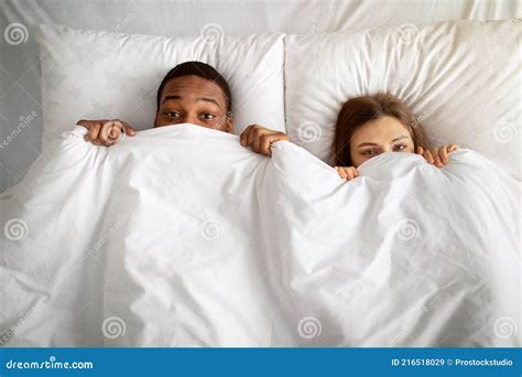 Playful Interracial Couple Hiding Under White Blanket In Bed Top View Stock Image Image Of
