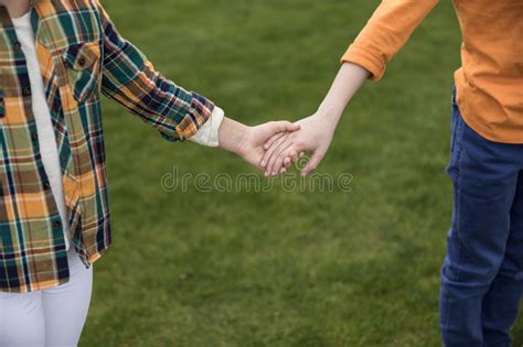Two Little Children Holding Hands While Standing On Green Grass Stock
