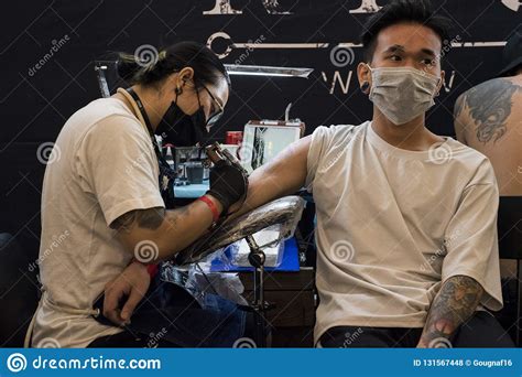 vietnamese-man-wearing-a-white-t-shirt-is-getting-a-tattoo-on-his-right-arm-by-recycle-tattoo