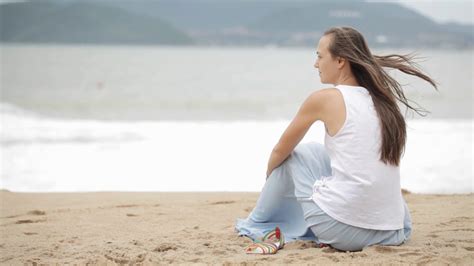 Young Woman Sitting On The Beach With Bad Weather And Looking On The Sea Stock Video Footage 00