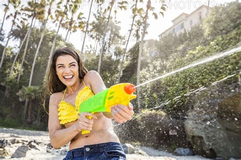 caucasian couple playing with squirt guns on beach photo12 tetra images mike kemp