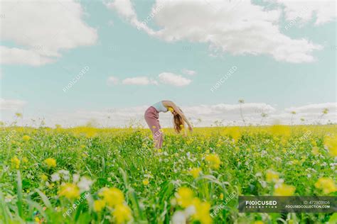 Young Woman Bending Over In A Flower Meadow In Spring — Rural Teen