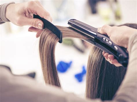 Close Up Of A Hairdresser Straightening Long Brown Hair With Hair Irons