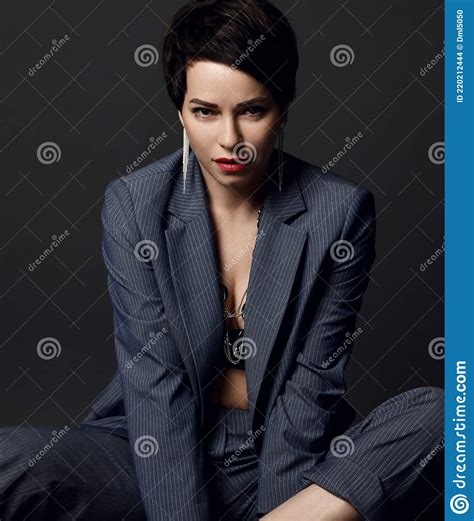 Attractive Short Haired Brunette Woman In Business Smart Casual Suit And Earrings Sitting