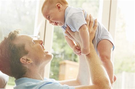 Mature Man Holding Up Baby Son Stock Photo