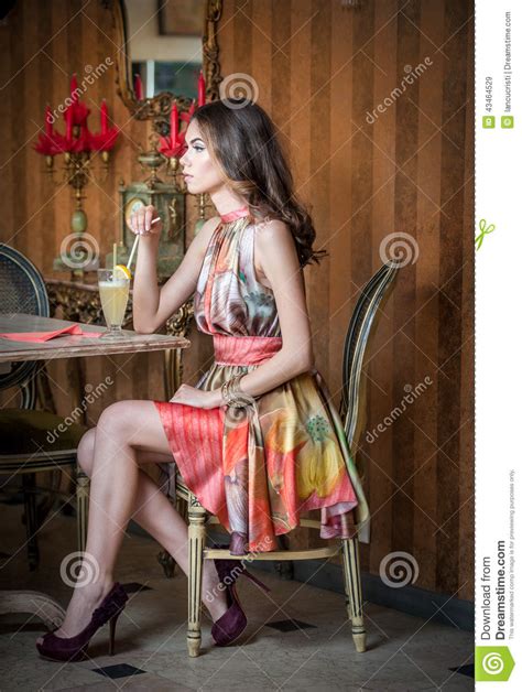 Fashionable Attractive Woman In Multicolored Dress Sitting In
