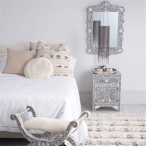 White and black moroccan style bedroom features walls draped in white sheer drapery panels lined with an ornate mirror placed above a black wood headboard lined with a queen bed dressed in crisp white bedding paired with a black damask bolster pillow as well as a black moroccan blanket flanked by black octagon shaped accent tables doubling as nightstands illuminated by aged brass swing arm. Grey & Mother of Pearl Inlay Scalloped Mirror (With images ...