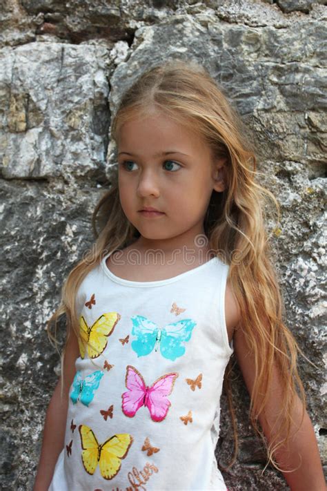 Portrait Of A Beautiful Little Girl Next To Stone Wall Stock Photo