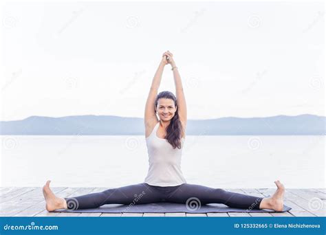 Young Attractive Smiling Woman Practicing Yoga On A Lake Stock Image