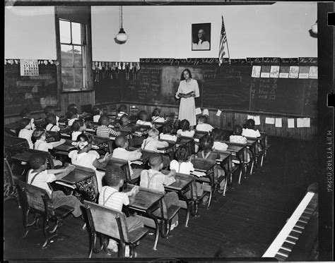 Teacher Reading To Class In Classroom With Old Fashioned Desks On