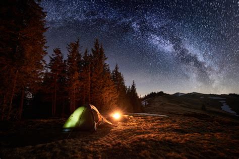 Night Camping Illuminated Tent And Campfire Near Forest Under Beautiful
