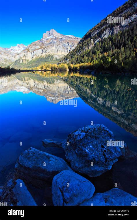 Lac De Derborence With Reflecting Mountain Range Under A Clear Blue Sky