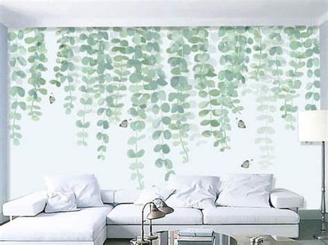 A Living Room With White Furniture And Green Leaves On The Wall
