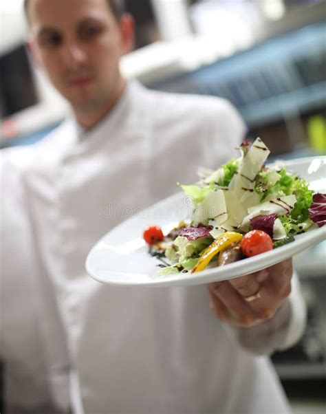 Chef Garnishing In The Kitchen Garnishing Their Salads Stock Photo