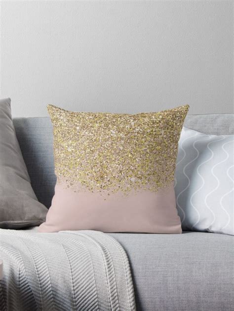 A Pink And Gold Pillow Sitting On Top Of A Gray Couch Next To Two Pillows