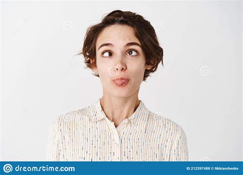 Silly And Funny Young Girl Squinting Showing Tongue To Have Fun Standing Playful On White