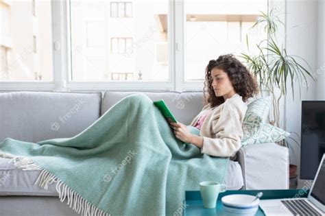 Vista Lateral De Una Mujer Recostada En Un Sofá Leyendo Un Libro Junto